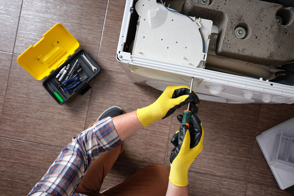 Technician repairing a washing machine for an appliance service customer in Fort Worth, TX